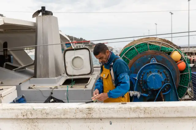 Pêcheur vérifiant les filets sur le pont d’un chalutier