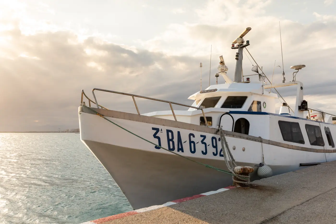 Proue d’un bateau de pêche amarré au quai au coucher du soleil